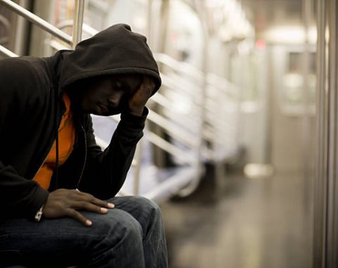African American male going through some difficult times, sitting on the New York City subway train. Copy space.
